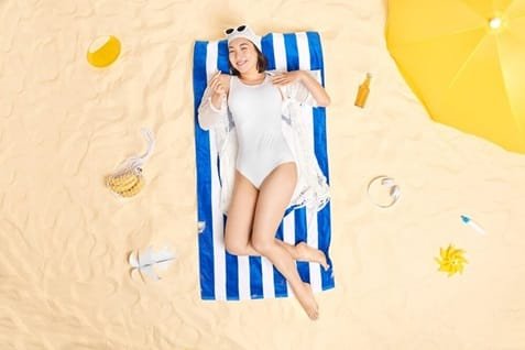 Vitamin D Source, Benefits and deficiencies 2 woman wears swimhat bathingsuit sunglasses forehead makes korean like sign poses sandy beach summer holidays enjoys nice weather vacation